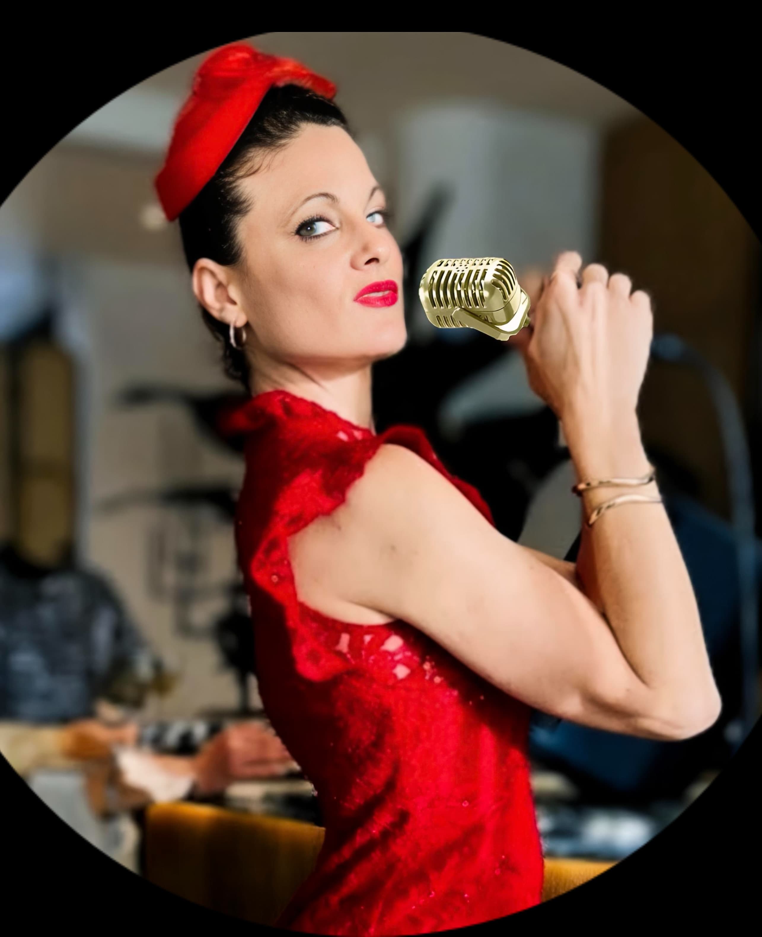 Woman in a red dress and pillbox hat posing with a vintage gold microphone.